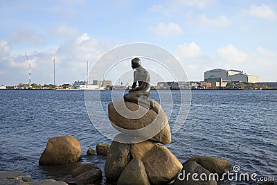 The sculpture of the little Mermaid on the background of the harbour quay of Copenhagen. Denmark Editorial Stock Photo