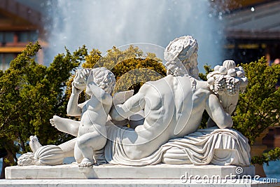 Sculpture of plaster in the form of a lying man and boy next to a background of bushes and splashes of a fountain Editorial Stock Photo