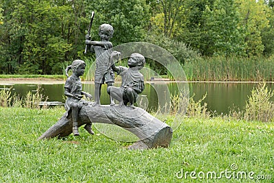 Sculpture of three children fishing on a log by Paul Anderson Editorial Stock Photo