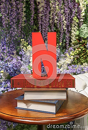 Scupture of a red letter N, initial and symbol mark of Netflix on a stack of books on a table. Editorial Stock Photo