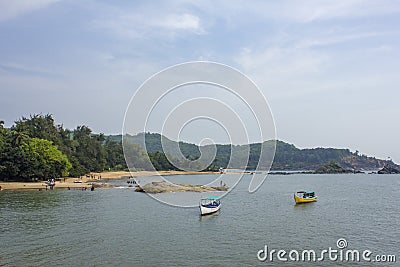 Sea bay with pleasure boats on the water, against the background of the green forest on the sandy beach and people resting Stock Photo