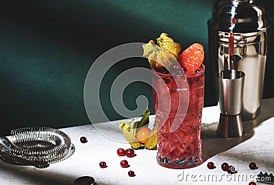 Sea breeze alcoholic cocktail with vodka, cranberries, grapefruit juice, orange and ice, decorated with physalis. Dark green Stock Photo