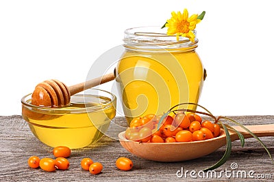 Sea buckthorn in wooden bowl with honey on old wooden table with white background. Fresh ripe berries with leaves Stock Photo