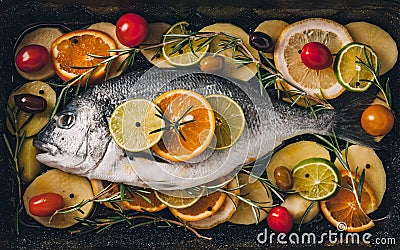 Sea gilt-head bream fish on ice with rosemary, lemon, orange and lime. Stock Photo