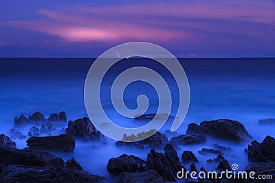 Deep blue ocean at dusk with distant flashes of lightning Stock Photo