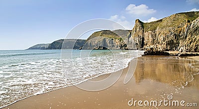 Sea meets sand reflecting the towering Pembroke Coastline between Lydstep and Manorbier Bay Stock Photo