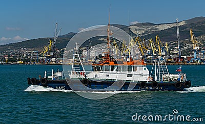Sea Pilot `Adis` is sailing in blue water Black Sea. White work boat `Adis` on Novorossiysk Commercial Sea Port and mountains Editorial Stock Photo
