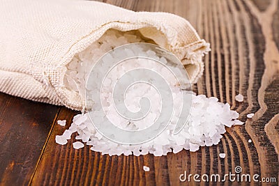 Sea salt in jute sack on wooden table. Stock Photo