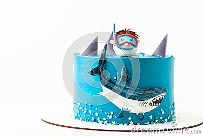 Sea and shark themed cake with blue cream cheese frosting on the white background. Diver in a mask. Snorkelling among the sharks. Stock Photo