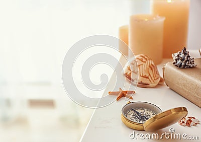 Sea shells with compass and burning candles on white shelf Stock Photo