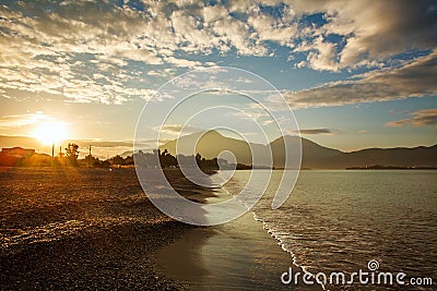 Sea shore in sunshine on background of mountains and sunset sky Stock Photo