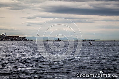 Sea side view on the Maiden`s Tower far away with grey clouds. Stock Photo