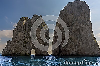 Sea Stacks and a natural arch of the Faraglioni rocks silhouetted against the early morning sunshine on the eastern side of the Stock Photo