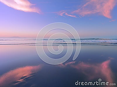 Sea at sunset with cloud reflections on sand Stock Photo