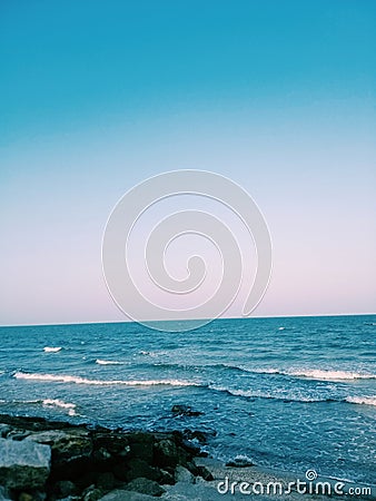 Sea wave with Blue sea and clearly sky. Evening light. Rock beach. Stock Photo