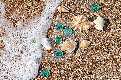 Sea wave, shells and glass pebbles on the wet sand Stock Photo