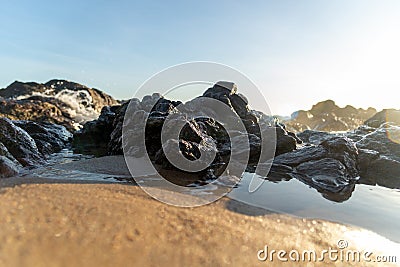 Sea waves lapping gently on the dark rocks of the beach Stock Photo