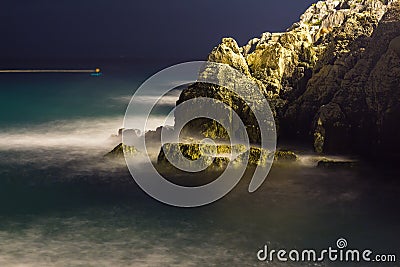 Sea waves lash line impact rock on the beach in night Stock Photo