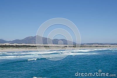 Sea, waves, sandy beach and mountains behind Stock Photo