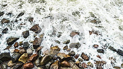 Sea waves slam into the sea rocks on the shore, sea foam on the shore rocks Stock Photo