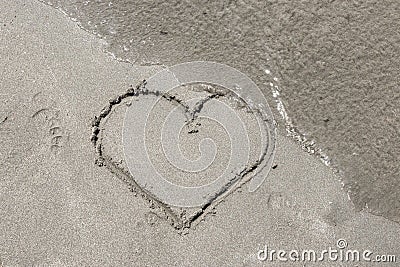 Waves wipe heart shape on sunny summer day on beach Stock Photo