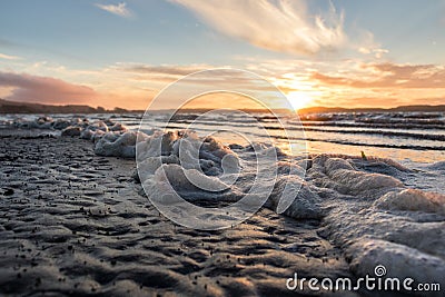 Seafoam on beach during beautiful sunset Stock Photo