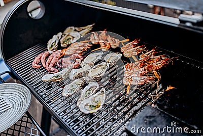 Seafood BBQ barbecue. Collection of octopus, oysters, clam, tiger shrimps grilled on grill Stock Photo