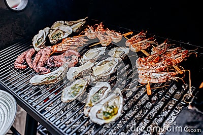 Seafood BBQ barbecue. Collection of octopus, oysters, clam, tiger shrimps grilled on grill Stock Photo