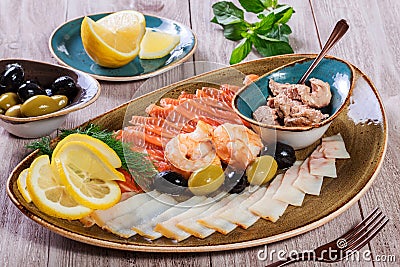 Seafood platter. Fresh cod liver, salmon, shrimp, slices fish fillet, decorated with herb, lemon Stock Photo