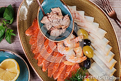 Seafood platter. Fresh cod liver, salmon, shrimp, slices fish fillet, decorated with herb, lemon and olives Stock Photo