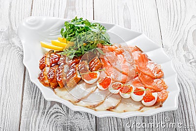 Seafood platter with salmon slice, smoke sturgeon, quail eggs with red caviar, slices fish fillet on wooden background Stock Photo