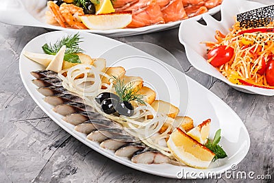 Seafood platter with smoked mackerel slice, fried potatoes, slices fish fillet, decorated with onion over rustic background Stock Photo