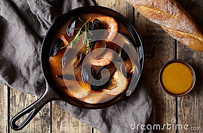 Seafood soup with fish, prawns, mussels tomato, lobster. Bouillabaisse. Rustic style background. Flat lay. Stock Photo