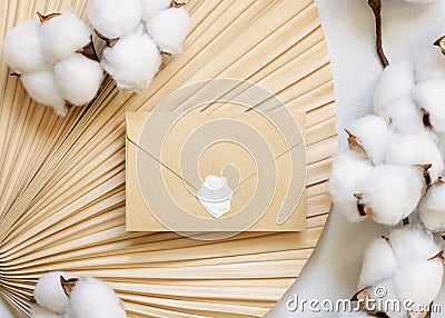 Sealed envelope on dried palm leaf with cotton flowers top view, wedding mockup Stock Photo
