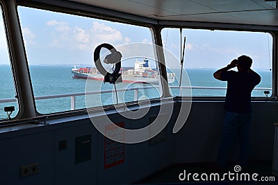 Seaman on the watch, looking at the container vessel passing Editorial Stock Photo