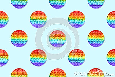 Seamless pattern of round rainbow silicone children`s toys antistress pop it or simple dimple on both sides on a blue background Stock Photo