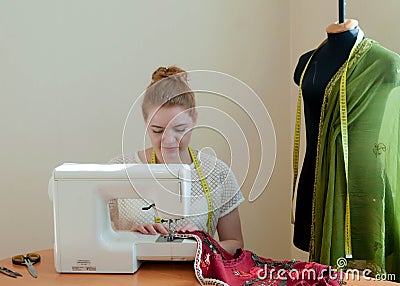 Seamstress with hand picked hair tailoring red vest with sawing machine Stock Photo