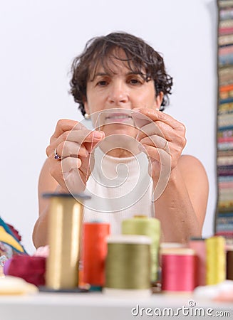 Seamstress threading a needle Stock Photo