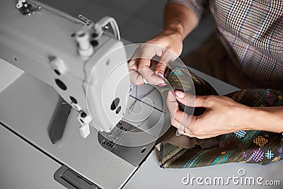 Seamstress working on modern electrical sewing machine making exclusive garments in fashion studio. Stock Photo
