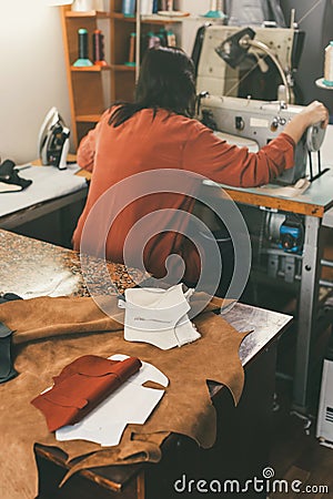 seamstress working with sewing machine in tailor shop with leather sheets Stock Photo