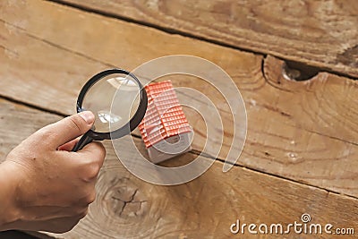 Searching a new home, real estate concept. Man looking to miniature toy house through a magnifying glass, Buy or sell the property Stock Photo