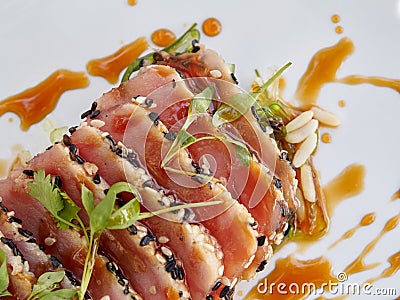 Seared ahi tuna slices on a bed of seaweed salad sprinkled with sesame seeds and oil and garnished with sprouts Stock Photo