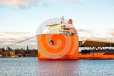 Seascape closeup side view of a large orange semi-submersible heavy-lift ship with large load entering harbor in Stockholm Sweden. Stock Photo