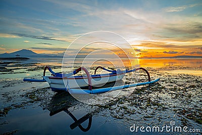 Seascape. Fisherman boat jukung. Traditional fishing boat at the beach during sunrise. Colorful sky. Amazing water reflection. Stock Photo