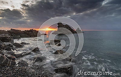 Dramatic clouds at sunrise hovering over sea Stock Photo