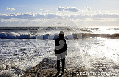 Seascape. Marine landscape with the figure of a woman. Wave on the sea breakwater. Stock Photo