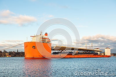 Seascape side view of a large orange semi-submersible heavy-lift ship with large load entering harbor in Stockholm Sweden. Stock Photo