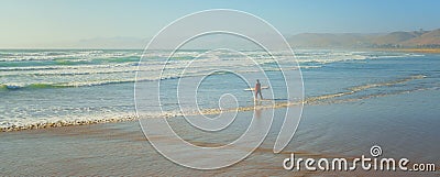 Seascape and silhoette of surfer with surf board, hills, and blue sky background Stock Photo