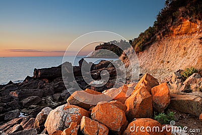 Seascape of Sunset with orange rocks on foreground Stock Photo