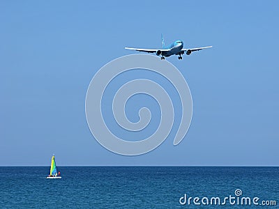 Seascape: vibrant sailboat and airplane over sea Editorial Stock Photo